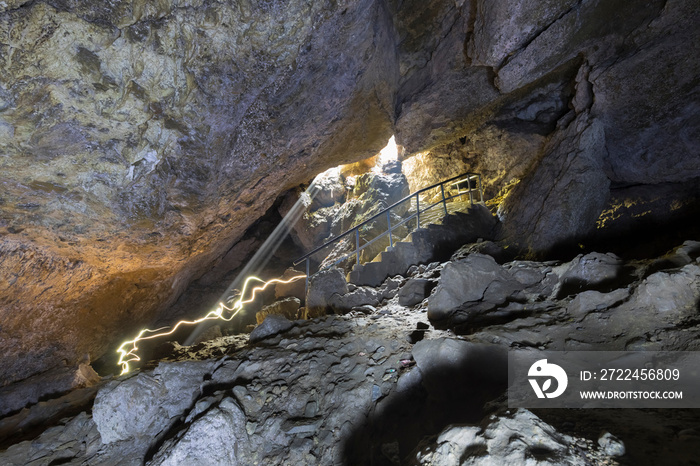 Inside batt cave people moving with light Nepal