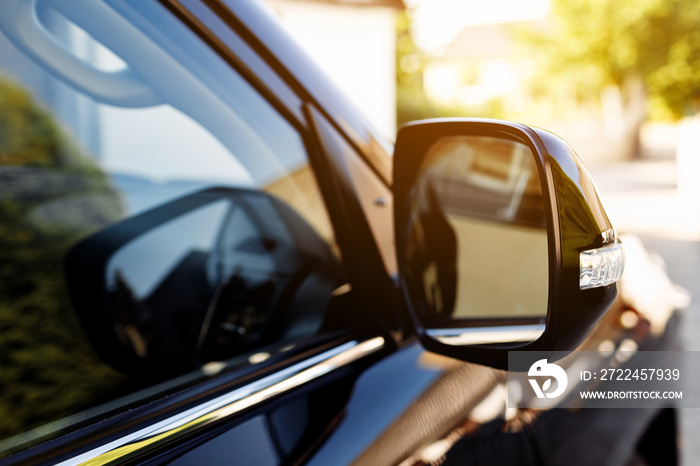 The rear view mirror on modern car on a black car. Rear view mirror car on the road. Close-up of Road safety while driving.