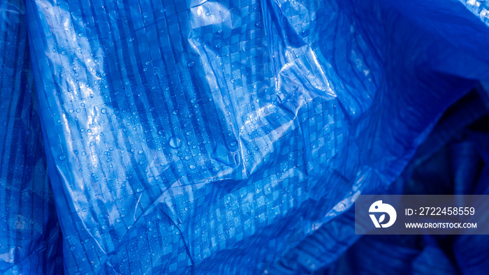 Vivid blue plastic Tarpaulin with water droplets on its surface.