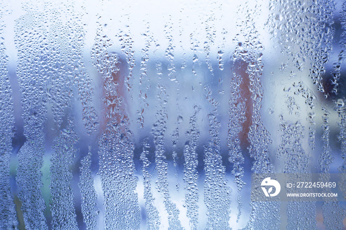 Misted glass background. Strong humidity in wintertime. Water drops from home condensation on a window