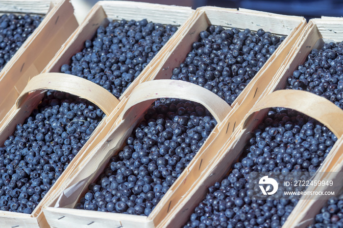 Large wooden baskets, full of blueberries, ready for sale. Farmers street food market. A fruit stand at riverside food market, summer sunny day.