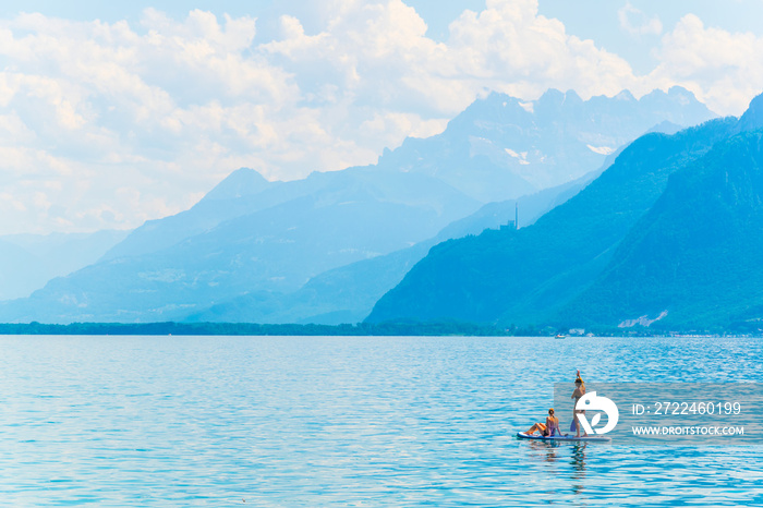 A couple is paddleboarding on geneva lake near Montreaux, Switzerland