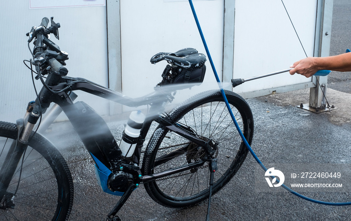 One people washes his bicycle with soap and sponge and takes care of the details. Service station with high pressure pump