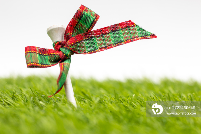 Golf Christmas Holiday with golf ball and Christmas ribbon on green grass