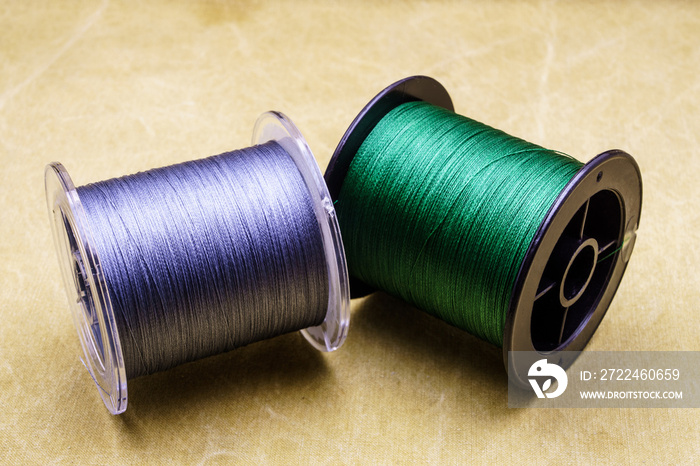 Spools of cords on the background of tarpaulin. Green and gray fishing line. Spools of braided fishing line