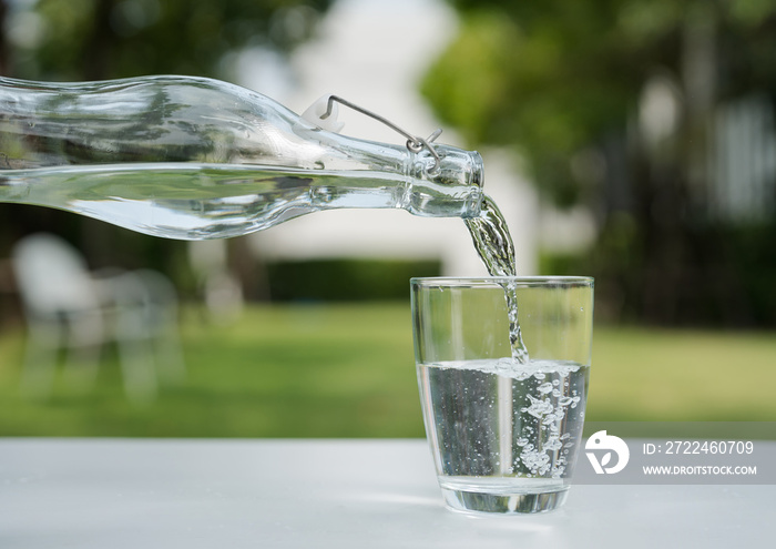 Pour the water from the water bottle into the glass.