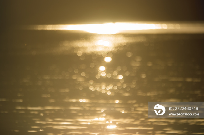 abstract blurry background if golden water surface at sunset