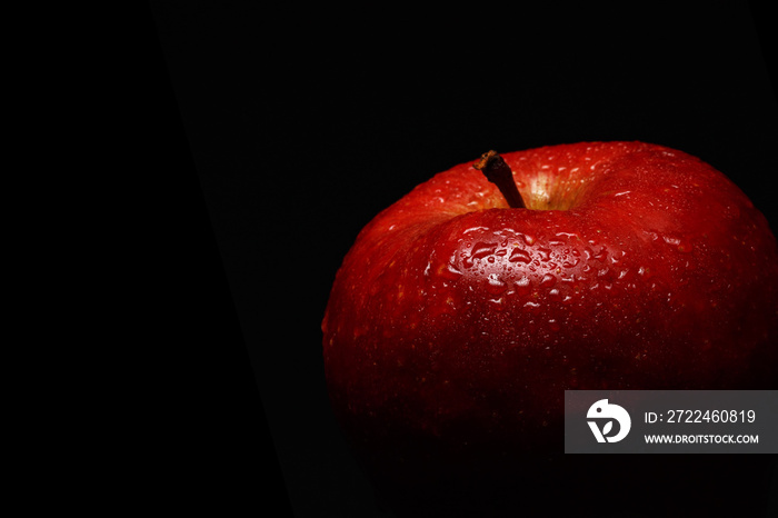 Appetizing red apple covered with drops of water on a black background. Close-up