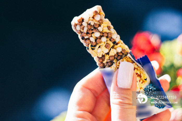 Woman holding a cereal bar ready to eat