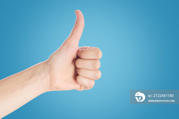 Positive gesture on a blue background. Hand show thumbs up sign, close up