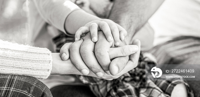 Concept of unity, support, protection, happiness. Child hand closeup into parents. Hands of father, mother, keep hand little baby. Black and white