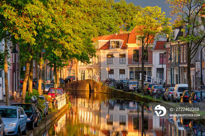 Delt canal with old houses and cars parked along on sunset