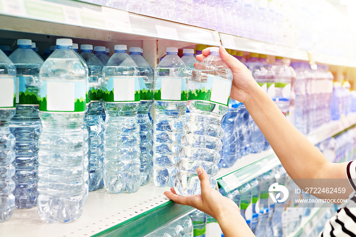 Hand with bottles of water in store