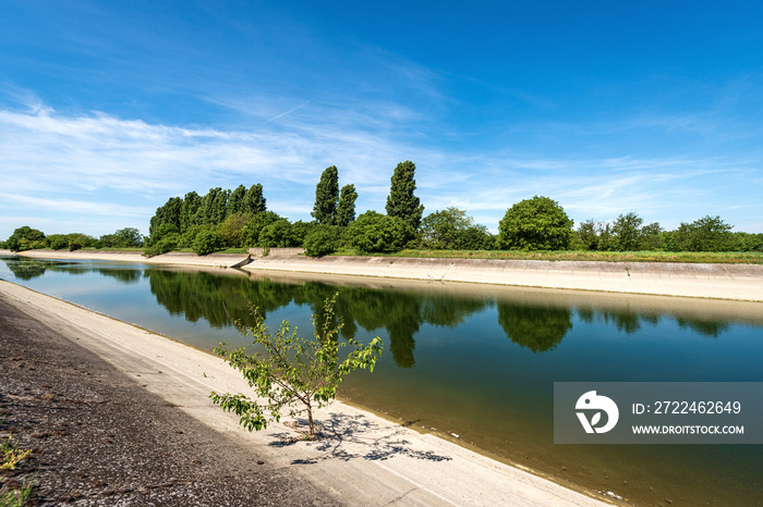 Reinforced concrete irrigation canal of the River Mincio in the Padan Plain or Po valley (Pianura Padana, italian). Mantua province, Italy, southern Europe.