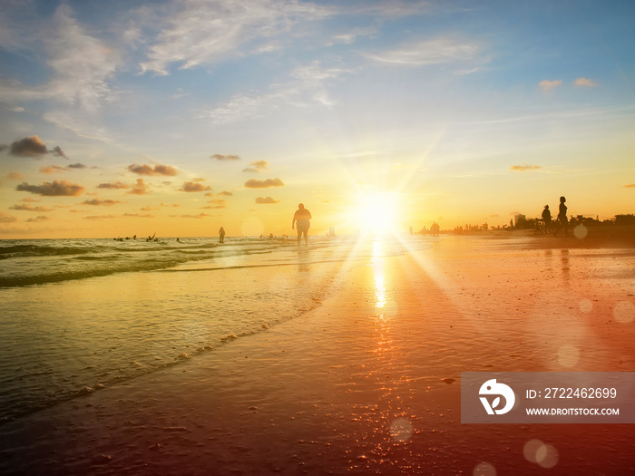 group of silhouetted people on public beach over orange colored sunset sky in Siesta key, Sarasota, Florida