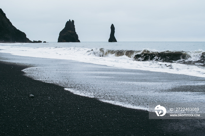 Famous panorama of the black sand beach in Iceland. Dark waves of Atlantic ocean waves covering the sand