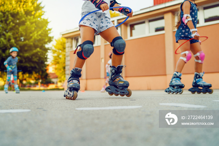 Close up on children’s legs wearing roller blades skates learning to ride on the asphalt in the school yard activities