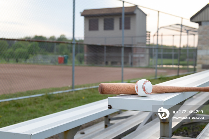 baseball and wooden bat on bleachers at a baseball field