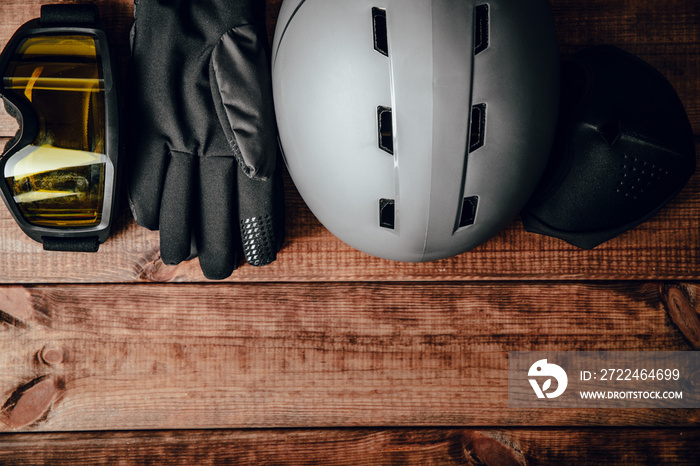 Skier’s equipment, snowboarder. Ski helmet, ski goggles and gloves on a wooden background. The concept of skiing, proper clothing and preparation for winter sports.