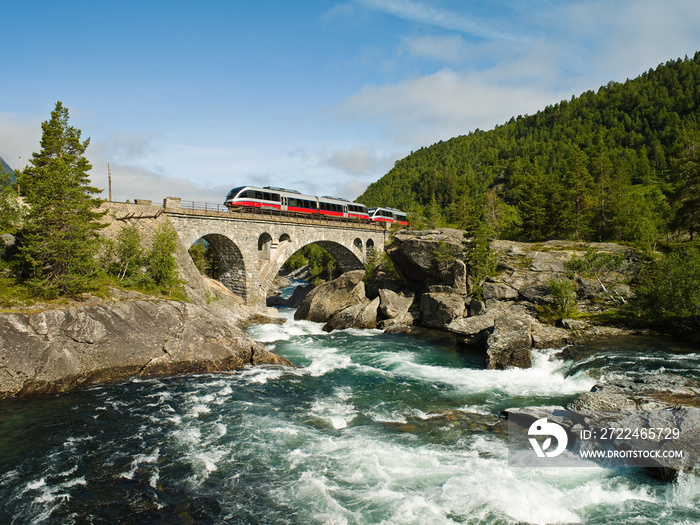 Train crossing bridge over Rauma river  in Romsdalen valley in Norway at summer