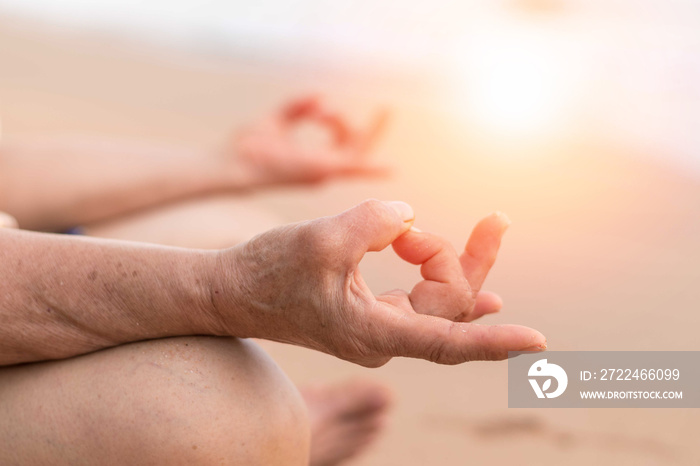 Meditate yoga hands of elderly woman doing meditation in silhouette sunset and lens flair effect.Healthcare, lifestyle concept. International Yoga Awareness Day