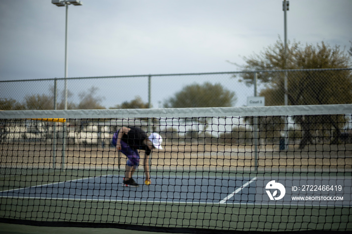 Woman playing pickleball match with whiffle ball and pickle ball paddle