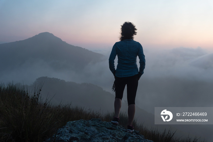 Woman standing in the bush feeling the sunset