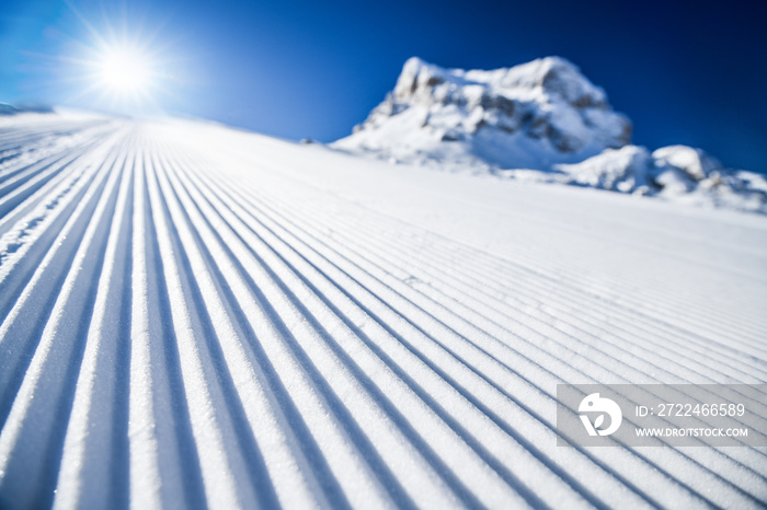 New groomed ski piste or slope. Lines in snow. Winter skiing background, fresh snow on slope.