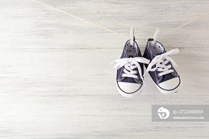 Baby sport shoes hanging on the clothesline on light wooden background