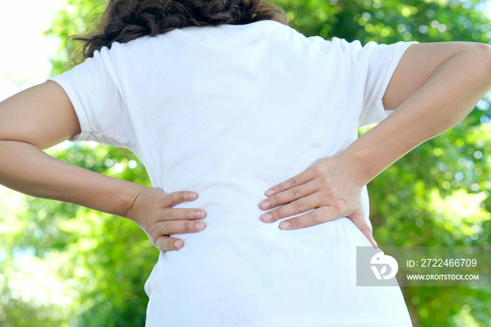 Woman’s hand She is caught at the waist and her back is painful at the back in the park. Cause of the exercise.