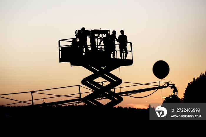 Silhouette of group of cameramen on the lift at a summer event