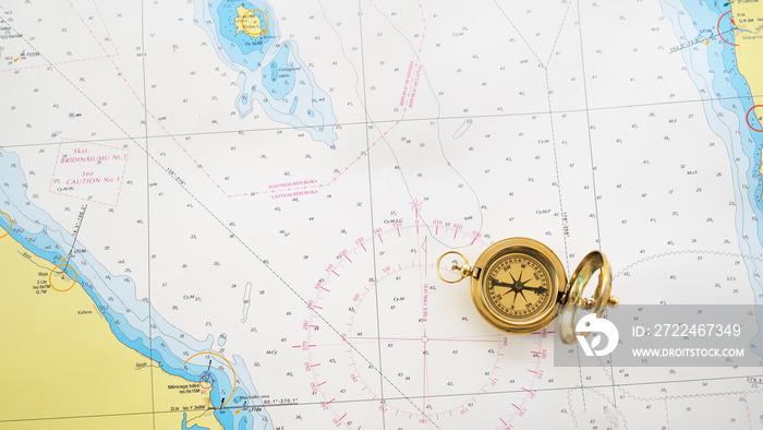 Retro styled golden compass (sundial) and old white nautical chart close-up. Vintage still life. Sailing accessories. Travel, navigation, history, collecting, hobby. Panoramic image, copy space