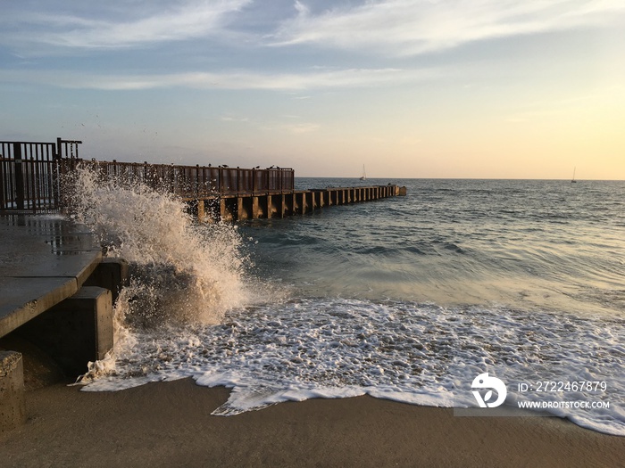 Waves crash against a jetty in Playa Del Rey, California, at sunset.