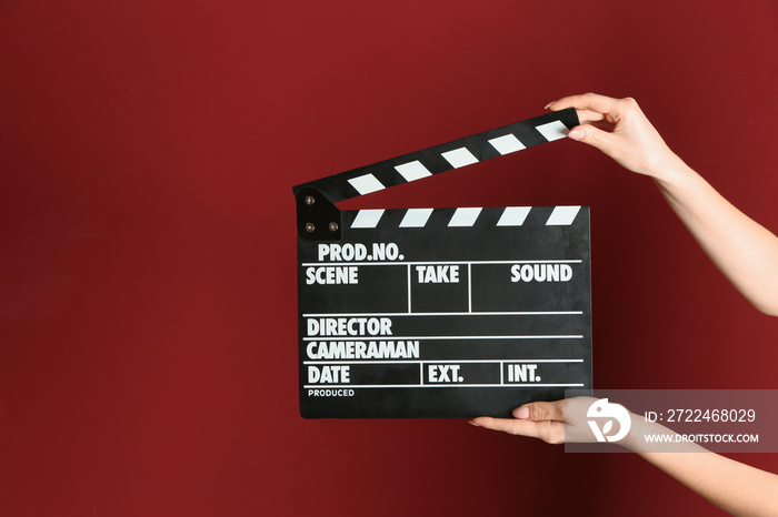 Female hands with cinema clapperboard on color background