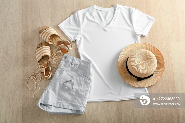 Composition with white t-shirt, shorts, hat and shoes on wooden background