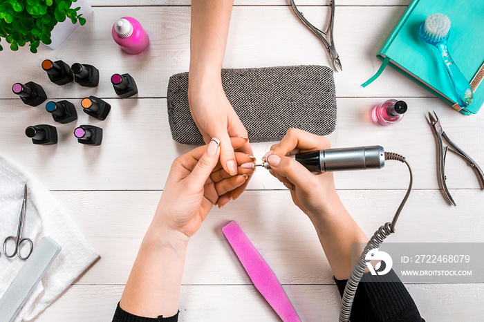 Manicure for the client. Close-up of the hands of a manicurist and client on a wooden background