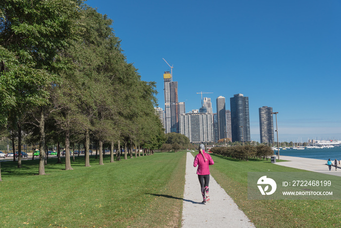 Healthy woman in fall sportswear running at daytime on park pathway