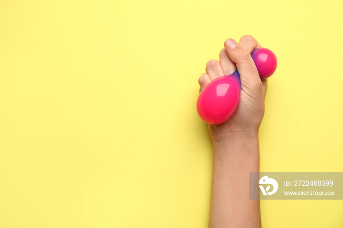 Female hand squeezing stress ball on color background