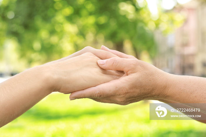 Mother and daughter holding hands together outdoors, closeup