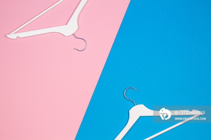 Two white wooden clothes hangers on pastel pink and blue background. Shopping, sale, promo, social media, new season concept