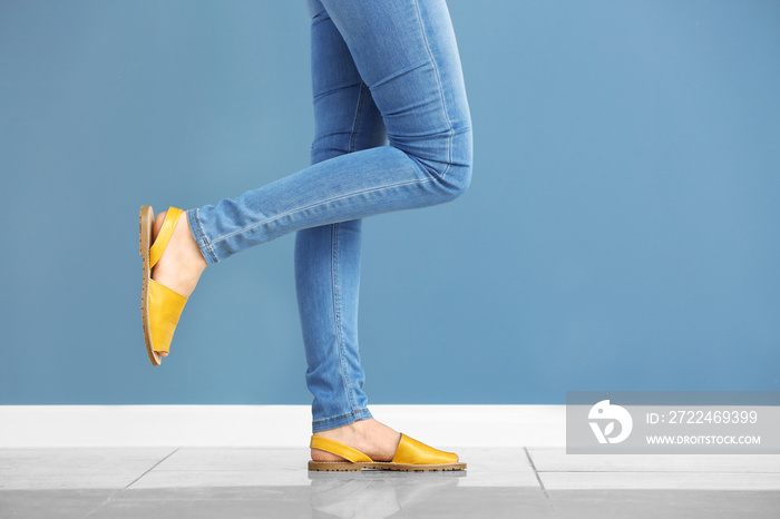 Young woman in stylish shoes against color wall