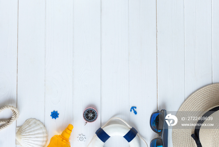 Summer vacation accessories, sunglasses, flip-flops, sunscreen, tiny swim ring, shells on a wooden background. Traveling essentials flat lay with copy space.