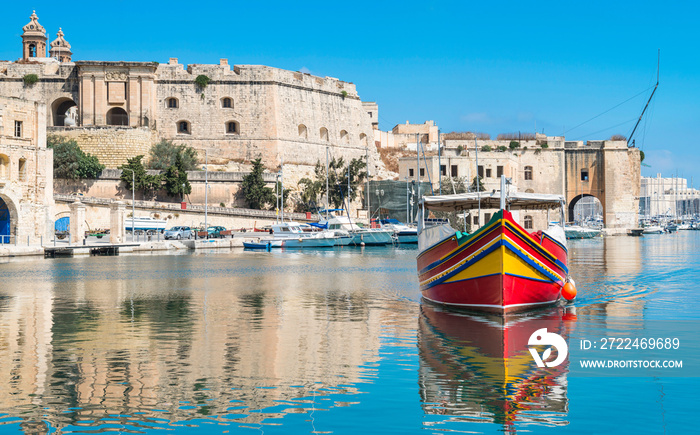 Traditionally painted passenger boat transports passengers between Valetta and Vittoriosa in Grand Valetta Bay in Malta. Mediterranean travel maritime panoramic background.