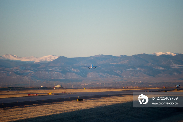 Airplane taking off with Rocky mountains front range in the background as viewed from Denver, Colorado