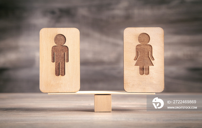 Male and female wooden symbols on balance scales.