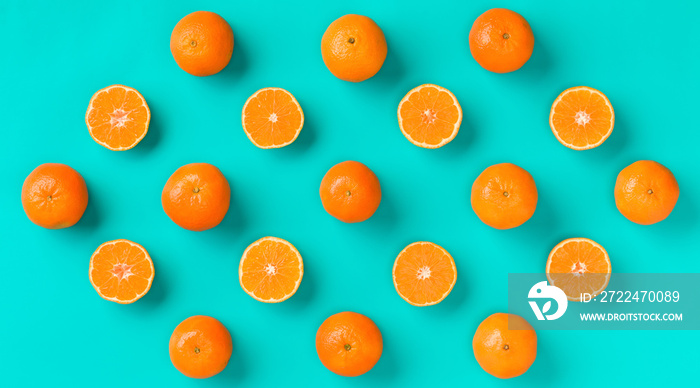 Fruit pattern of fresh mandarin slices on blue background. Flat lay, top view. Pop art design, creative summer concept. Half of citrus in minimal style. Tangerine.