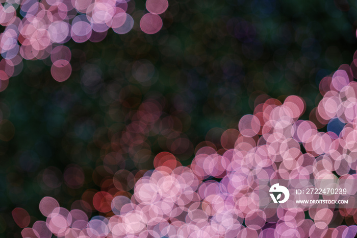 Illuminated abstract round red, purple, blue and magenta bokeh on dark background. Colourful glitter bokeh from out of focus view of decoration bulbs.