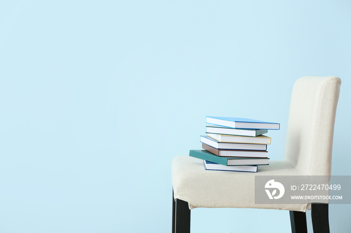 Stack of books on chair near color wall