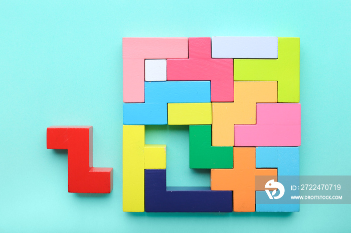 Multicolored puzzle, hand and cubes on a mint background