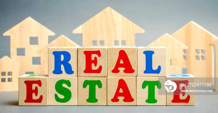 Wooden blocks with the word Real estate and wooden houses. Market value and real estate analytics. Pricing. Construction industry. Building property